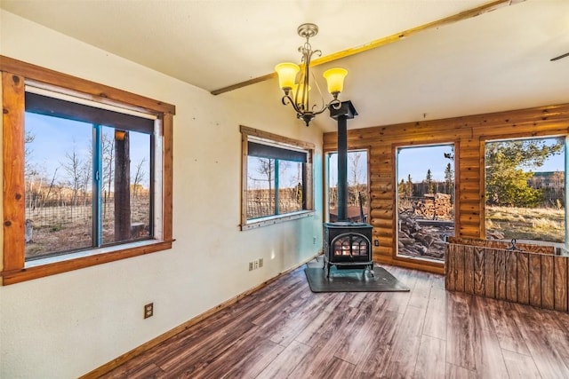 259 Falcon Rd, Como, CO 80432 - unfurnished room with a wood stove, log walls, wood finished floors, a chandelier, and healthy amount of natural light