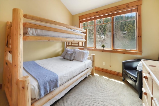 bedroom with vaulted ceiling, light colored carpet, and baseboards