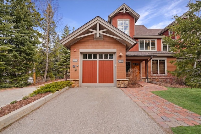 craftsman-style house with stone siding, roof with shingles, a garage, and aphalt driveway