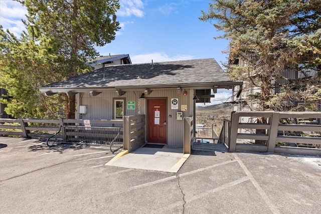 chalet / cabin with fence, uncovered parking, and roof with shingles