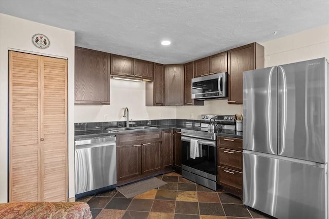 kitchen featuring a sink, dark brown cabinetry, dark countertops, and stainless steel appliances