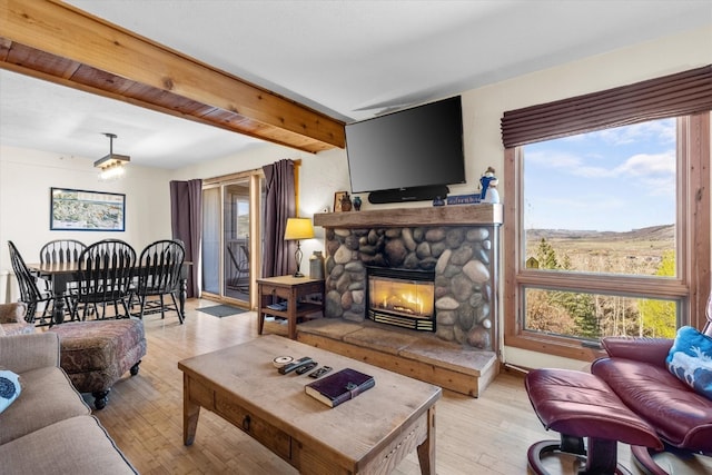 living room with light wood-style floors, beam ceiling, a wealth of natural light, and a fireplace