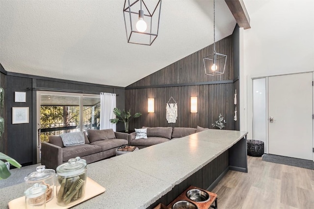 1127 Ski Hill Rd Unit 106, Breckenridge, CO 80424 - kitchen featuring high vaulted ceiling, light wood finished floors, a kitchen breakfast bar, and wooden walls