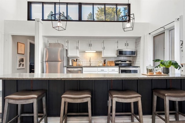 1127 Ski Hill Rd Unit 106, Breckenridge, CO 80424 - kitchen with stainless steel appliances, white cabinetry, tasteful backsplash, a sink, and a towering ceiling
