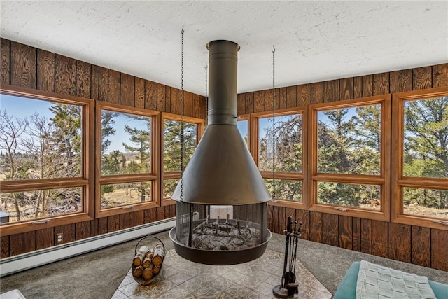 sunroom / solarium with a baseboard heating unit, a wood stove, and a healthy amount of sunlight