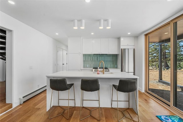 kitchen featuring baseboard heating, a sink, refrigerator, and light wood-style flooring