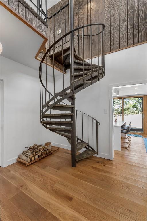 staircase featuring wood finished floors, a high ceiling, and baseboards
