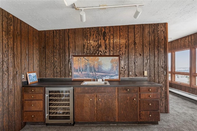 bar with wooden walls, a sink, beverage cooler, and a textured ceiling