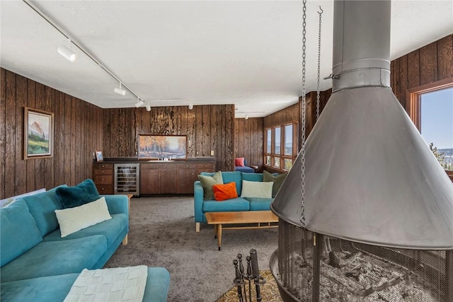 living room with beverage cooler, rail lighting, wood walls, and carpet