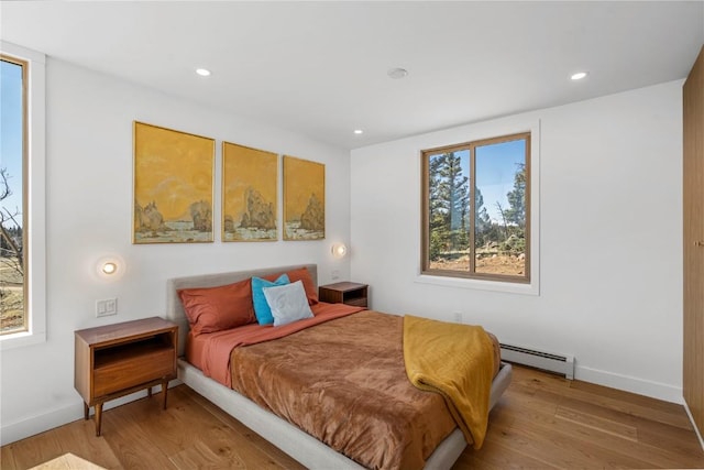 bedroom with light wood-type flooring, baseboard heating, baseboards, and recessed lighting