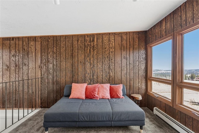 bedroom with a baseboard radiator, wooden walls, and carpet flooring