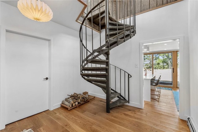 stairs featuring baseboards, baseboard heating, and wood finished floors