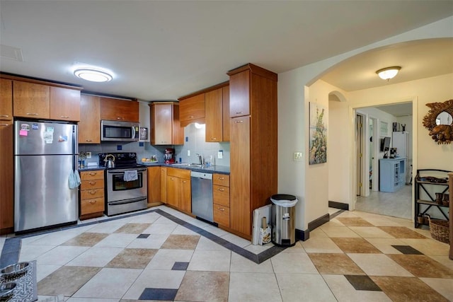 2415 Val Disere Cir, Steamboat Springs, CO 80487 - kitchen featuring stainless steel appliances, dark countertops, arched walkways, and light tile patterned floors