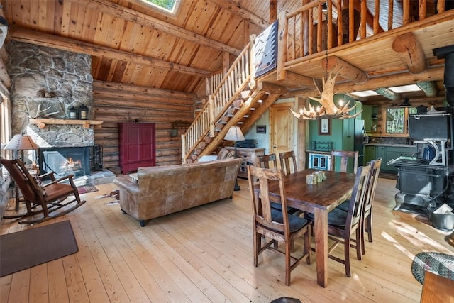 633 French Pass Cir, Jefferson, CO 80456 - dining room with log walls, stairs, a wood stove, a wood ceiling with exposed beams, and light wood-style floors
