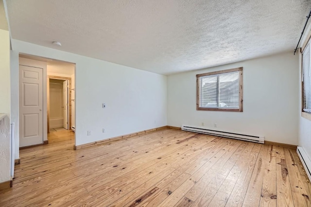 empty room featuring a baseboard heating unit, baseboards, a textured ceiling, and light wood-style floors