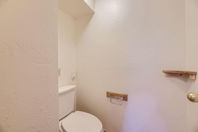 bathroom with a textured wall and toilet