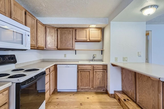 kitchen featuring light wood finished floors, open shelves, a sink, white appliances, and a textured ceiling