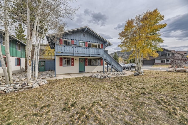 rear view of property featuring board and batten siding, a wooden deck, and stairs