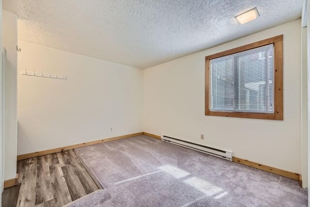 spare room with a baseboard heating unit, wood finished floors, baseboards, and a textured ceiling