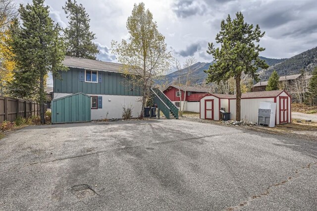 view of front of home featuring a shed, board and batten siding, an outdoor structure, a mountain view, and fence