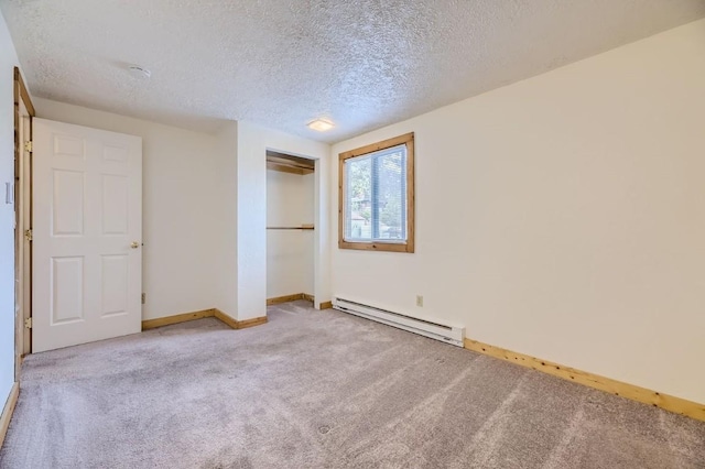 unfurnished bedroom with a baseboard heating unit, baseboards, carpet, and a textured ceiling