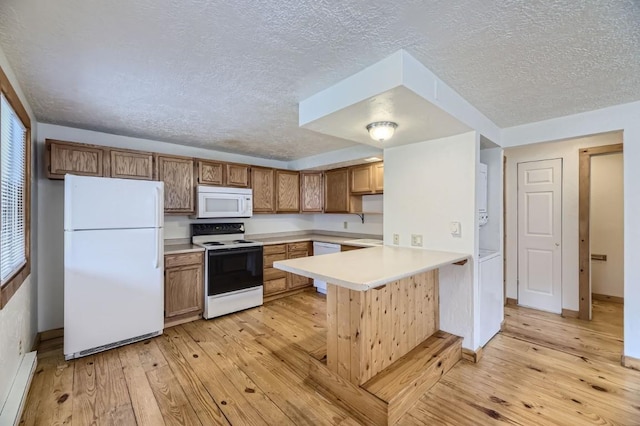 kitchen featuring a peninsula, a textured ceiling, light wood-style floors, white appliances, and a baseboard radiator