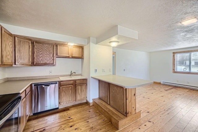 kitchen with a sink, a peninsula, light wood-style flooring, a textured ceiling, and appliances with stainless steel finishes