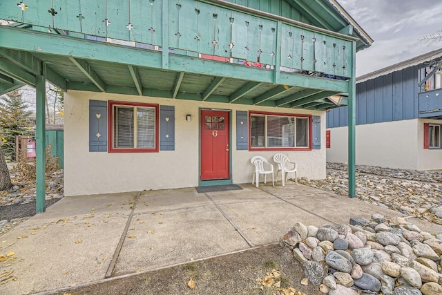 entrance to property featuring stucco siding, electric panel, and board and batten siding