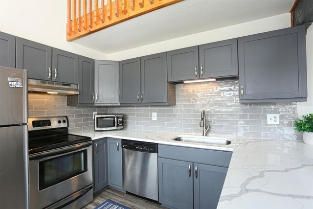 9876 Ryan Gulch Rd Unit F303, Silverthorne, CO 80498 - kitchen featuring light stone counters, under cabinet range hood, stainless steel appliances, a sink, and decorative backsplash