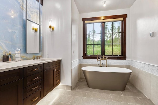 228 Cottonwood Cir, Breckenridge, CO 80424 - full bath featuring healthy amount of natural light, double vanity, a soaking tub, tile patterned floors, and a wainscoted wall