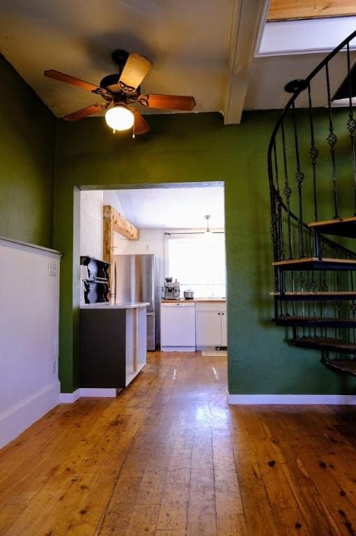 436 Clifton Ave, Yampa, CO 80483 - unfurnished living room with wood-type flooring, beam ceiling, ceiling fan, baseboards, and stairs