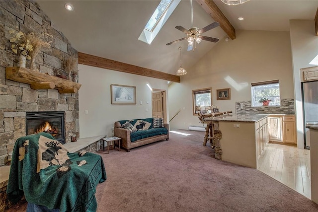 61 Pine Cir, Breckenridge, CO 80424 - living area with beamed ceiling, a baseboard radiator, a stone fireplace, light carpet, and ceiling fan