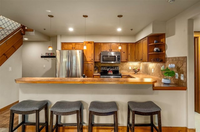435 Ore House Plz Unit 301, Steamboat Springs, CO 80487 - kitchen featuring stainless steel appliances, brown cabinets, open shelves, tasteful backsplash, and decorative light fixtures