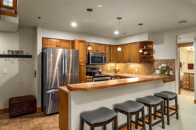 435 Ore House Plz Unit 301, Steamboat Springs, CO 80487 - kitchen featuring stainless steel appliances, brown cabinetry, open shelves, a kitchen breakfast bar, and recessed lighting