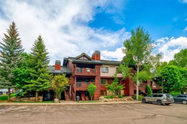 435 Ore House Plz Unit 301, Steamboat Springs, CO 80487 - view of front of home featuring stairway, uncovered parking, a chimney, and a balcony