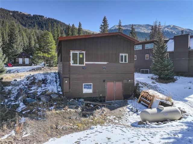 snow covered back of property featuring a mountain view