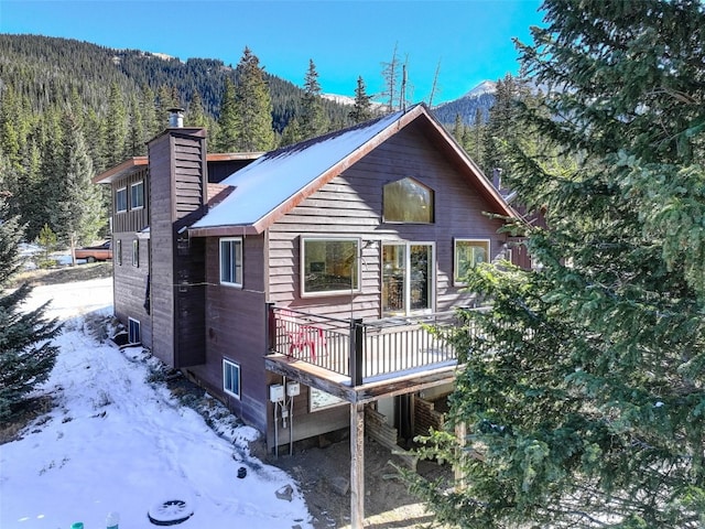 snow covered rear of property with a mountain view