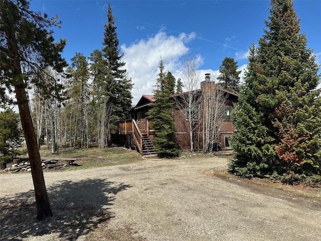 view of side of property featuring stairs, a chimney, and a deck