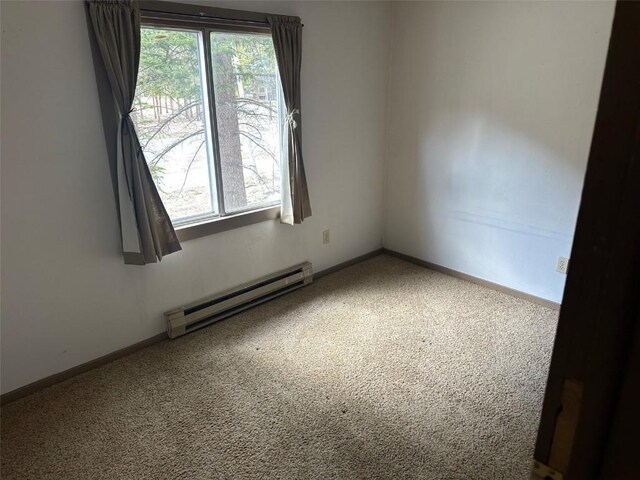 carpeted spare room with baseboards and a baseboard heating unit
