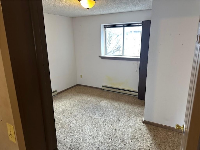 carpeted spare room with baseboards, a textured ceiling, a baseboard heating unit, and baseboard heating