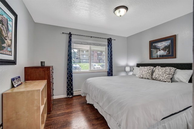 1153 Straight Creek Dr Unit 204, Dillon, CO 80435 - bedroom featuring dark wood-style floors, a baseboard radiator, baseboards, and a textured ceiling