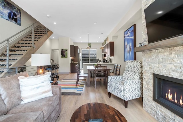 living room featuring a stone fireplace and light wood-style flooring