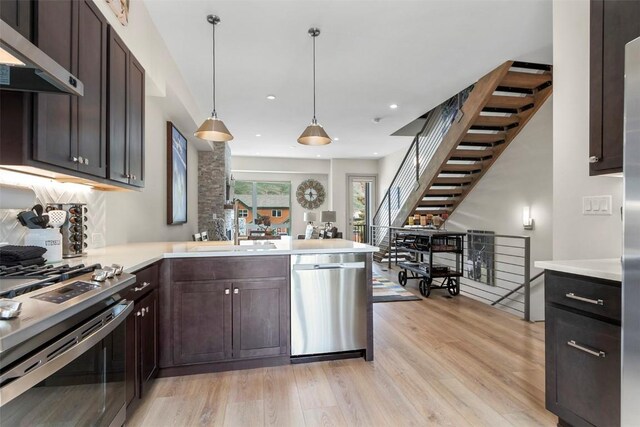 kitchen featuring light countertops, light wood-style flooring, appliances with stainless steel finishes, and extractor fan