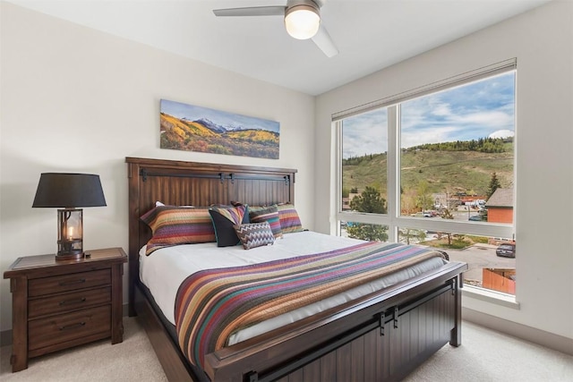 bedroom featuring light colored carpet, baseboards, and ceiling fan
