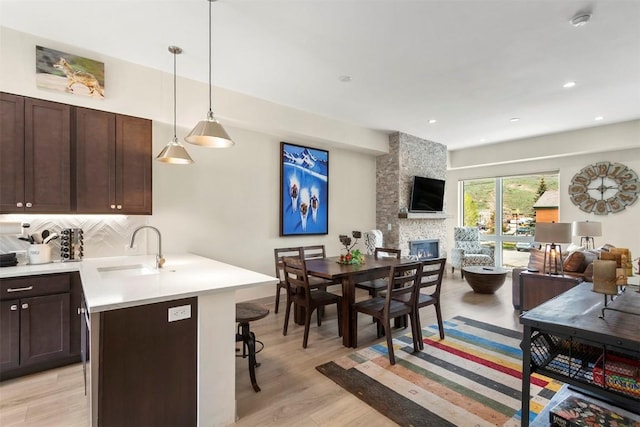 kitchen with dark brown cabinetry, a breakfast bar, a sink, light countertops, and open floor plan