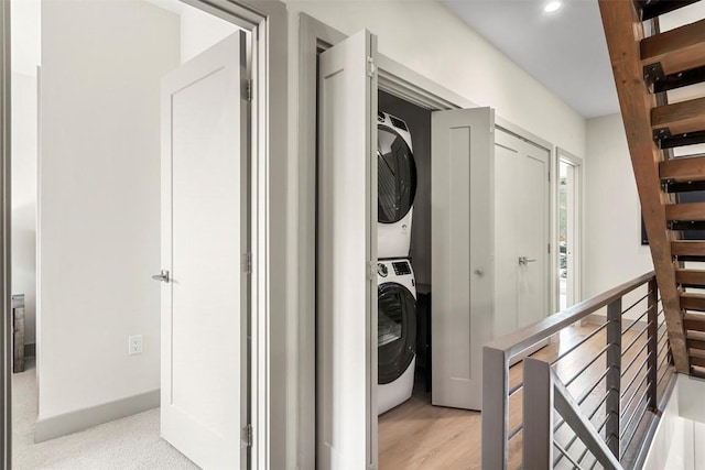 clothes washing area featuring laundry area, recessed lighting, light wood-style flooring, and stacked washing maching and dryer