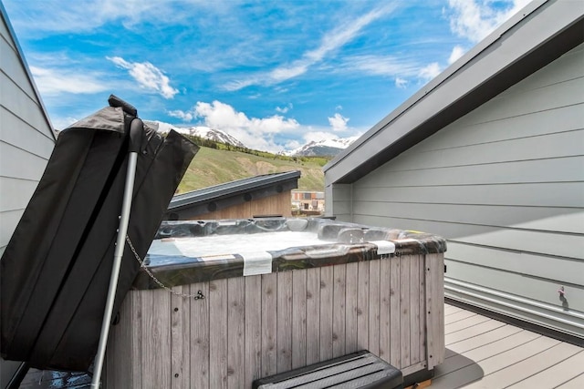 wooden deck featuring a hot tub and a mountain view
