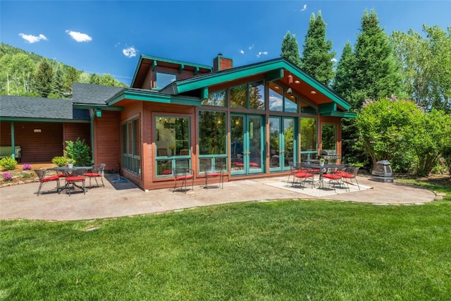 31650 Mt Werner Rd, Steamboat Springs, CO 80487 - rear view of property featuring a chimney, a patio area, a lawn, and a sunroom
