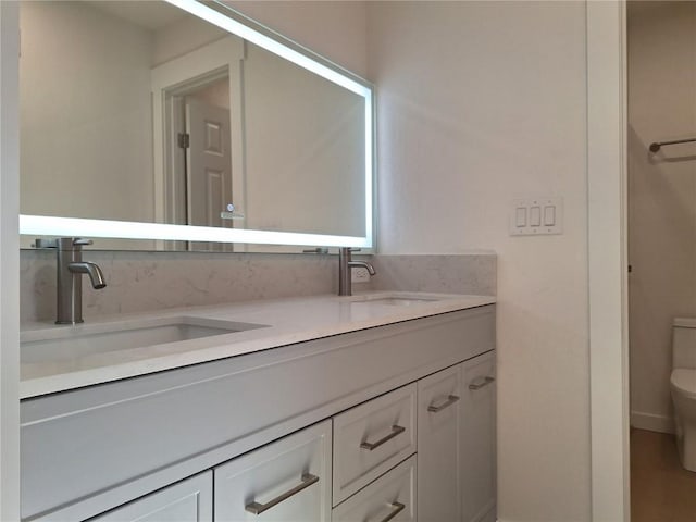 full bathroom featuring double vanity, a sink, and toilet