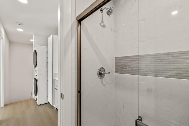 bathroom featuring stacked washer / dryer, a shower stall, recessed lighting, and wood finished floors